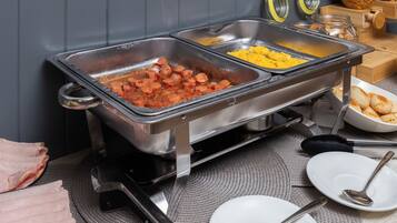 Un buffet proposant une variété de plats, notamment des saucisses, des œufs brouillés et des viennoiseries.