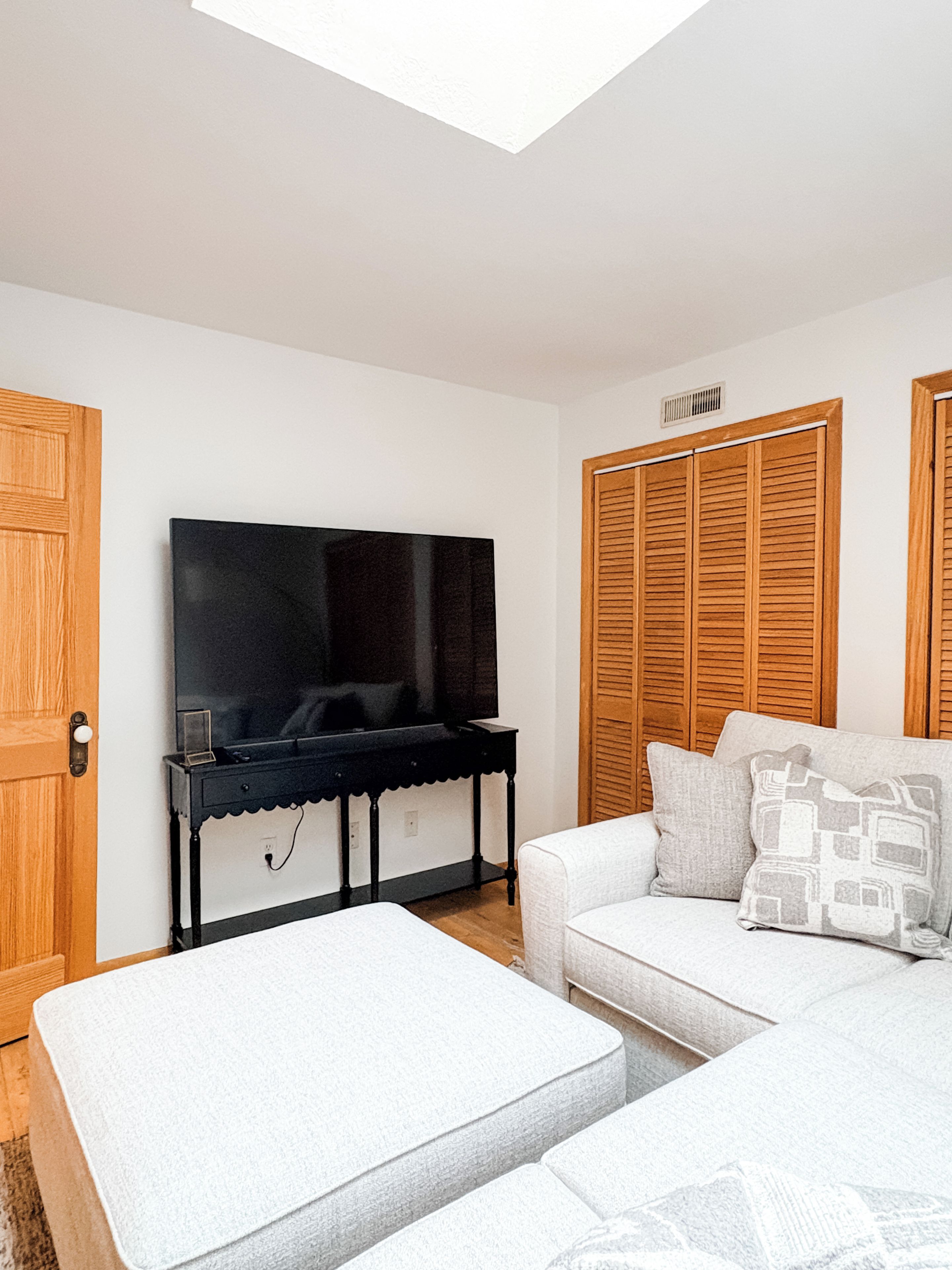 Cozy lounge with plush seating, oversized ottoman, and large TV