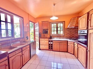 Una cocina con armarios de madera, un lavamanos de acero inoxidable, un microondas y una estufa.