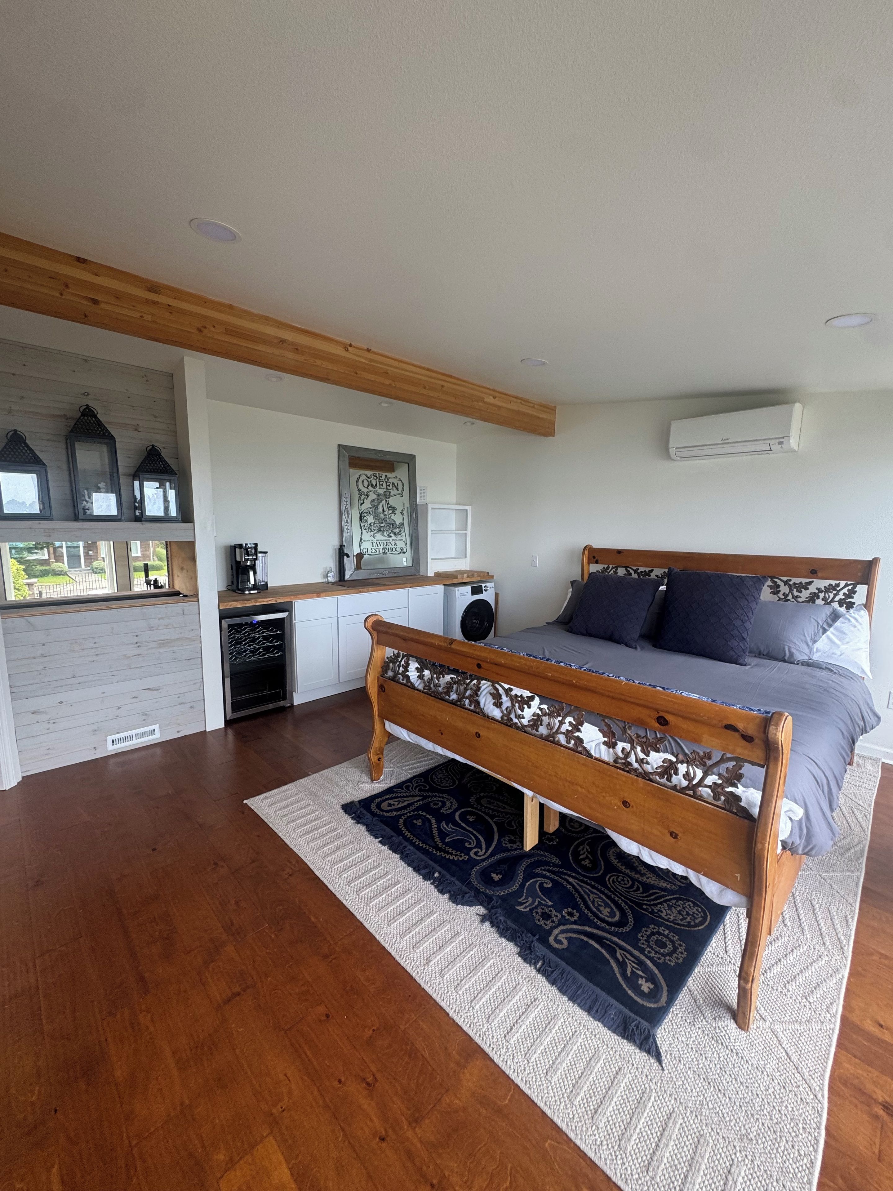 Een slaapkamer met een houten bed, een keukenhoek en uitzicht op de omgeving.