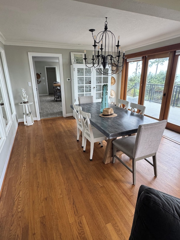 A dining area with a dark wood table, white chairs, and a chandelier.