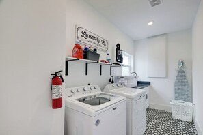 Ein Waschraum mit einem Feuerlöscher, einem Schild mit der Aufschrift 'Laundry Co' und einem gemusterten Boden.