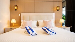 Une chambre d’hôtel avec un grand lit, deux tables de chevet, une lampe et deux serviettes sur lesquelles figure le nom de l’hôtel.
