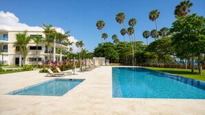Un complexe hôtelier doté d’une grande piscine, de chaises longues et de palmiers.