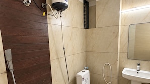 A bathroom with a shower, toilet, sink, and a water heater mounted on the wall. - Ashok Vatika Hotel Siddhant (Indore)