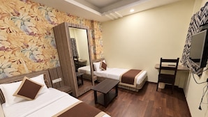 A hotel room with two beds, a desk, a chair, a mirror, and a television. - Ashok Vatika Hotel Siddhant (Indore)