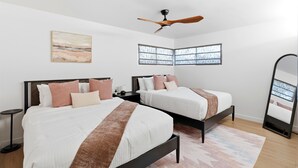 Quarto com duas camas, um ventilador de teto, um quadro e um espelho grande.