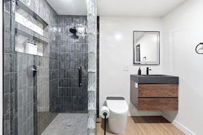 Une salle de bain moderne équipée d’une douche, de toilettes et d’un meuble-lavabo.