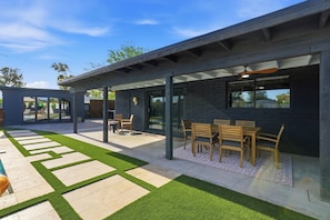 Une terrasse extérieure moderne avec une piscine, un espace salon couvert et une pelouse bien entretenue.