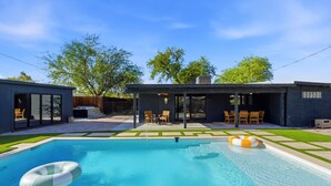 Uma área de piscina moderna ao ar livre, piscina azul e límpida, um flutuador e um espaço coberto com cadeiras.