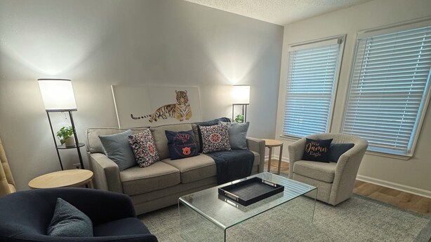 Ein Wohnzimmer mit einer Couch, Sesseln, einem Couchtisch und einem Teppich.