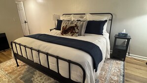 Ein Schlafzimmer mit einem Bett, einem Nachttisch, einem Beistelltisch, einem Teppich und einer Tür.