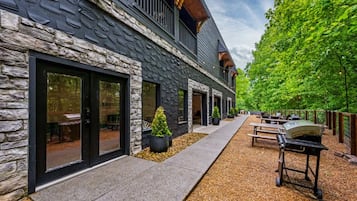 A building with stone facade, outdoor seating, and a barbecue grill.