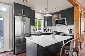 Eine moderne Küche mit einer großen Kochinsel, Edelstahlgeräten und einer Wand mit Holzpaneelen.