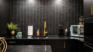 A modern kitchen with black tiles, a gold faucet, and a built-in oven.