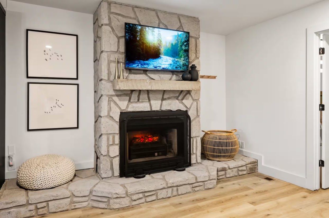 A stone fireplace with a television above it, framed by two wall-mounted pictures.