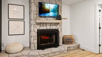 A stone fireplace with a television above it, framed by two wall-mounted pictures.