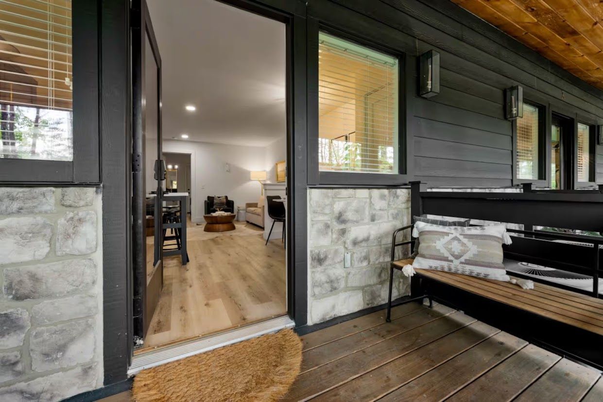 Un intérieur moderne avec un mur en pierre, un plancher en bois, un banc et une vue sur un espace de vie comprenant un canapé et une table basse.