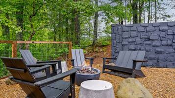 An outdoor seating area with Adirondack chairs, a fire pit, and a stone wall.