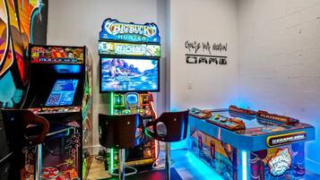 Ein Raum mit Spielautomaten, darunter ein 'Big Buck Hunter'-Spiel, und einer Wand mit Graffiti-Kunst.