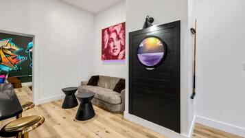 A modern living room with a sofa, a round wall-mounted TV, and a painting on the wall.