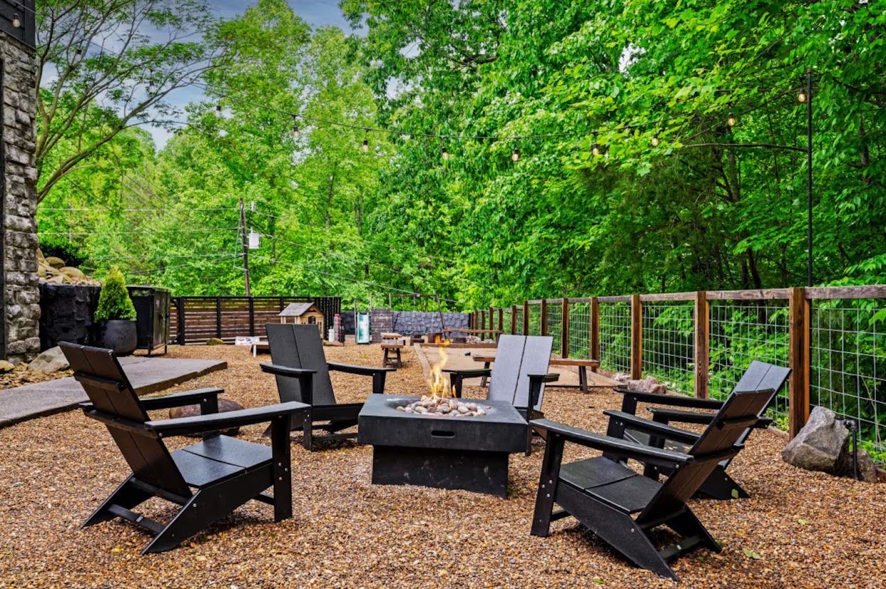 Une terrasse extérieure dotée d’un foyer, de sièges et d’un mur en pierre.