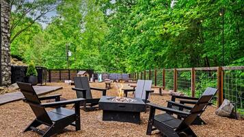 An outdoor patio with a fire pit, seating, and a stone wall.