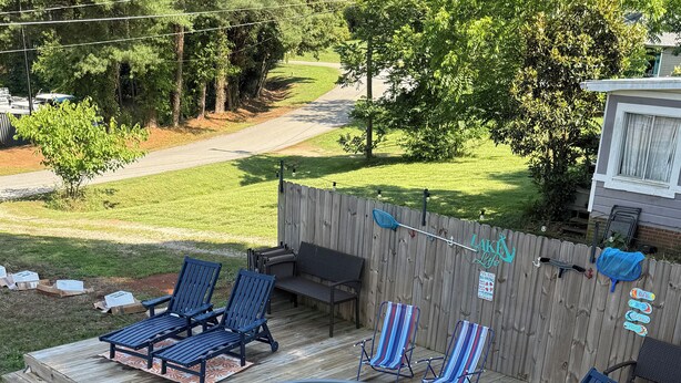 Un jardin avec un jacuzzi entouré de chaises longues, une terrasse en bois et un chemin en pierre.
