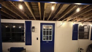 Une porte bleue portant le numéro 115, un mur blanc et un plafond en bois avec des poutres apparentes.