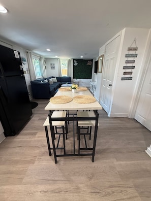 A modern kitchen with a dining table, black chairs, and a black refrigerator. - Flip-Flop down to the Lake; Cozy 2-bedroom apartment with AC (MOORESVILLE)