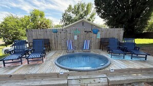 Une terrasse en bois avec un jacuzzi, des chaises longues et une clôture en bois.
