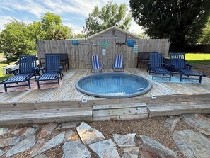 A wooden deck with a hot tub, lounge chairs, and a wooden fence. - Cozy 2-bedroom apartment with AC in charming Mooresville (MOORESVILLE)
