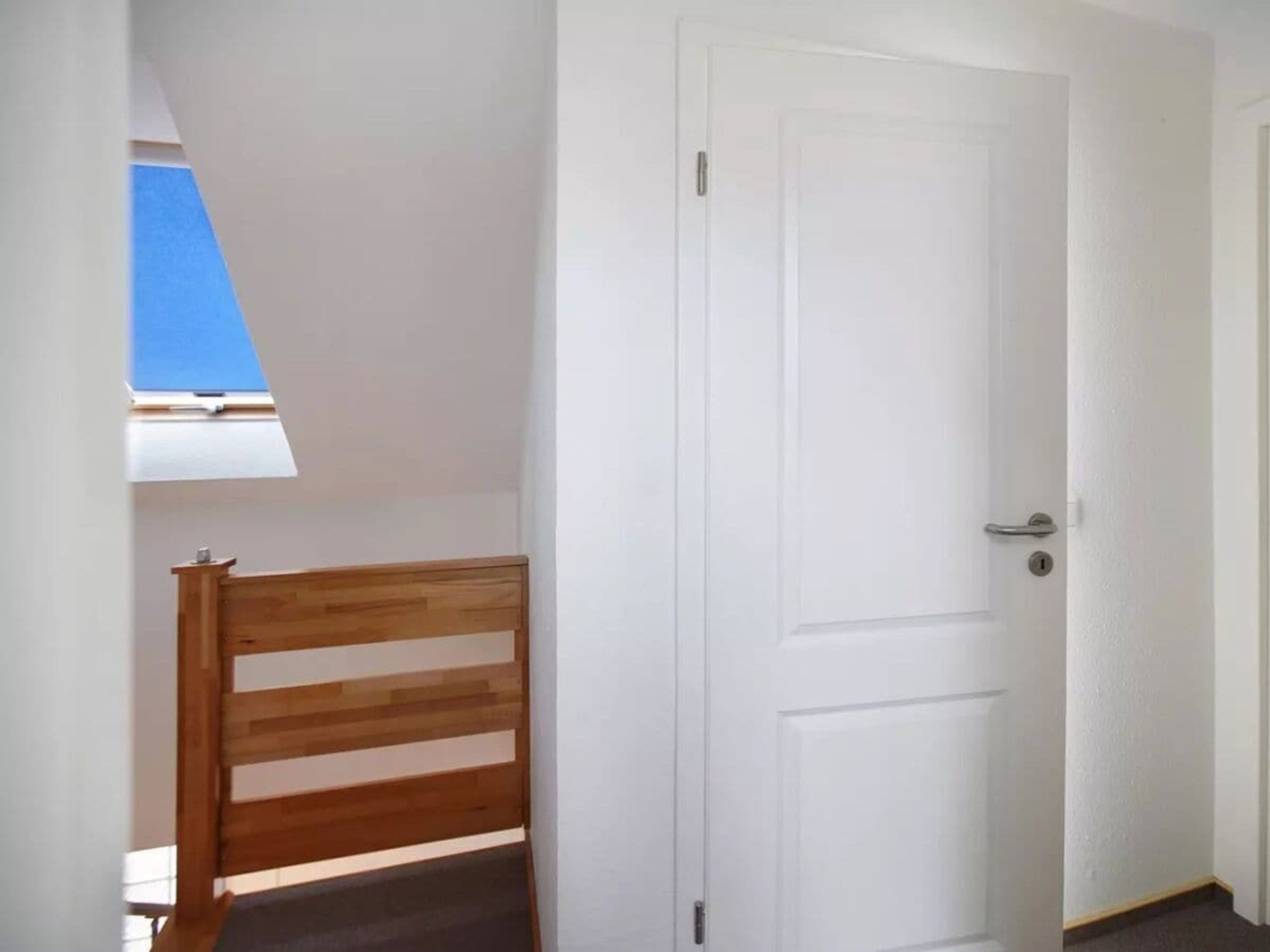 Ein Zimmer mit einer weißen Tür, einem Holzstuhl und einem Oberlicht.