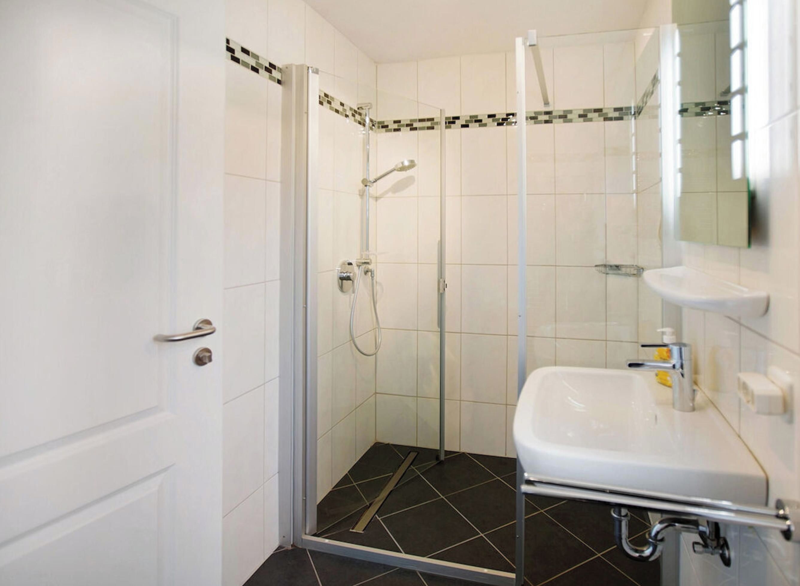 Ein Badezimmer mit Dusche, Waschbecken und einer Tür.