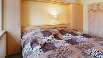 A bedroom with a bed, a bedside lamp, a wardrobe, and a hanging coat rack.
