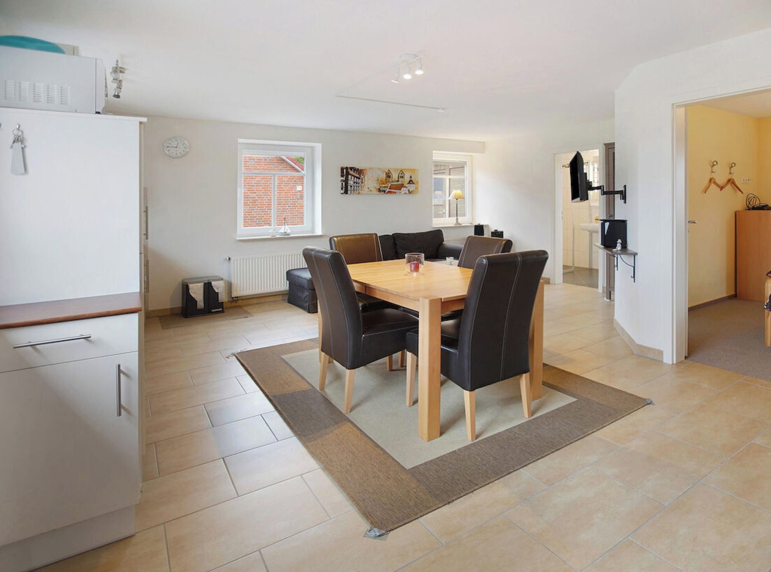 Una cocina moderna con comedor, que incluye una mesa central con sillas, un refrigerador y una ventana con persianas.