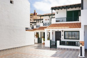 A narrow street with white buildings, terracotta roofs, and a tiled pavement. - Home2Book Family House, Pool & Garage (Puerto Santiago)