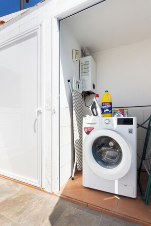 A laundry area with a washing machine, a detergent bottle, and a drying rack. - Home2Book Family House, Pool & Garage (Puerto Santiago)