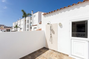 Um edifício branco com telhado em telhas, uma janela e uma porta.