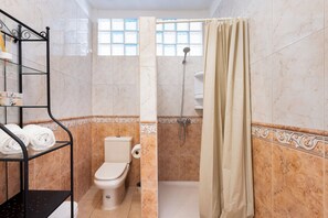 A bathroom with a toilet, shower, and a glass shelf with towels. - Home2Book Family House, Pool & Garage (Puerto Santiago)