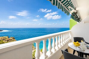 Ein Balkon mit weißer Brüstung, der auf ein klares, blaues Meer blickt.