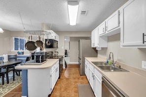 A modern kitchen with white cabinets, a stainless steel sink, and a coffee maker. - Lovely 2-bedroom home in Royse City (royse city)