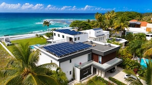 Une villa moderne dotée de panneaux solaires, d’une piscine et offrant une vue sur l’océan.