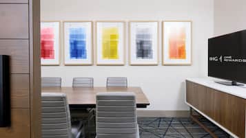 A conference room with a long table, six chairs, and a television on a stand.