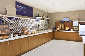 A breakfast area with a sign for 'EXPRESS START BREAKFAST,' a bakery section, and a display of hot food options. - Holiday Inn Express Cedar Rapids South - Arpt Area by IHG (Cedar Rapids)