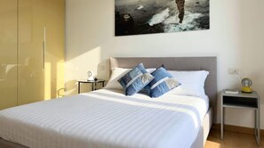 A bedroom with a bed, pillows, a bedside table, a nightstand, a lamp, and a painting on the wall. - Casa Cenni Bright 2BR M1 Citylife (Milan)
