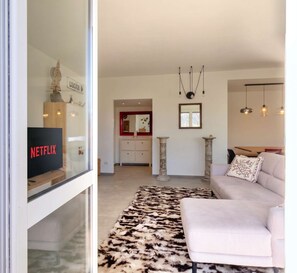 A modern living room with a sofa, a patterned rug, and a television displaying the Netflix logo. - Casa Cenni Bright 2BR M1 Citylife (Milan)