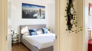 A bedroom with a bed, a nightstand, a wall clock, and a painting. - Casa Cenni Bright 2BR M1 Citylife (Milan)