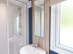 A bathroom with a glass shower enclosure, a white sink, and a mirror. - Kestrel Lodge (Coalville)