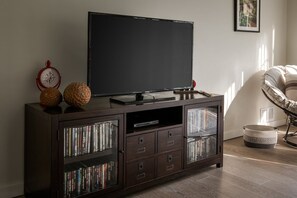 A dark wood entertainment center with a flat-screen TV, DVD player, and a clock.